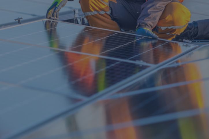 Un tecnico con regolari DPI sta posizionando un pannello fotovoltaico in mezzo ad altri pannelli.
