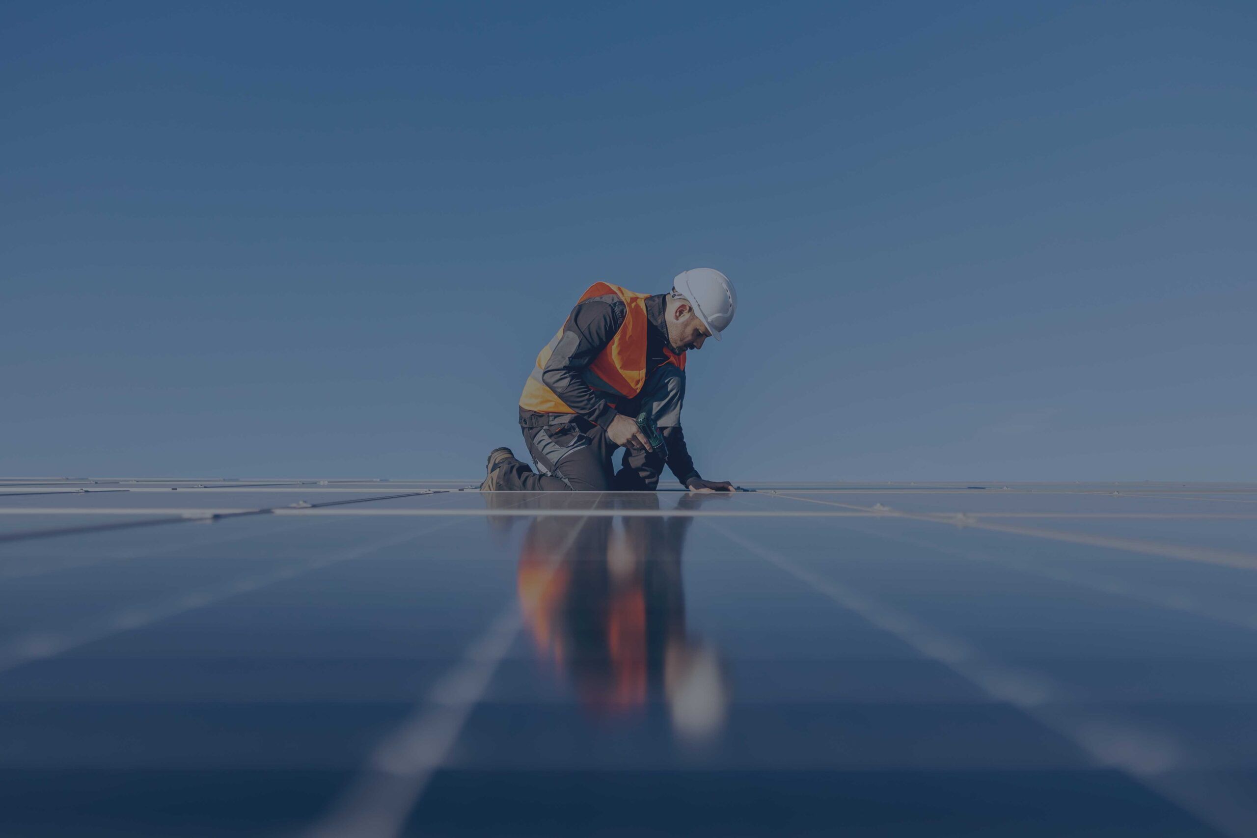 Un tecnico con regolari DPI sta posizionando un pannello fotovoltaico in mezzo ad altri pannelli.