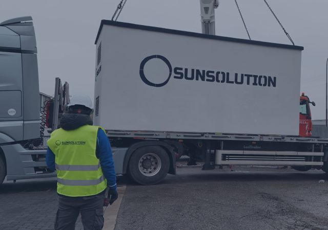 Un tecnico con regolari DPI sta posizionando un pannello fotovoltaico in mezzo ad altri pannelli.