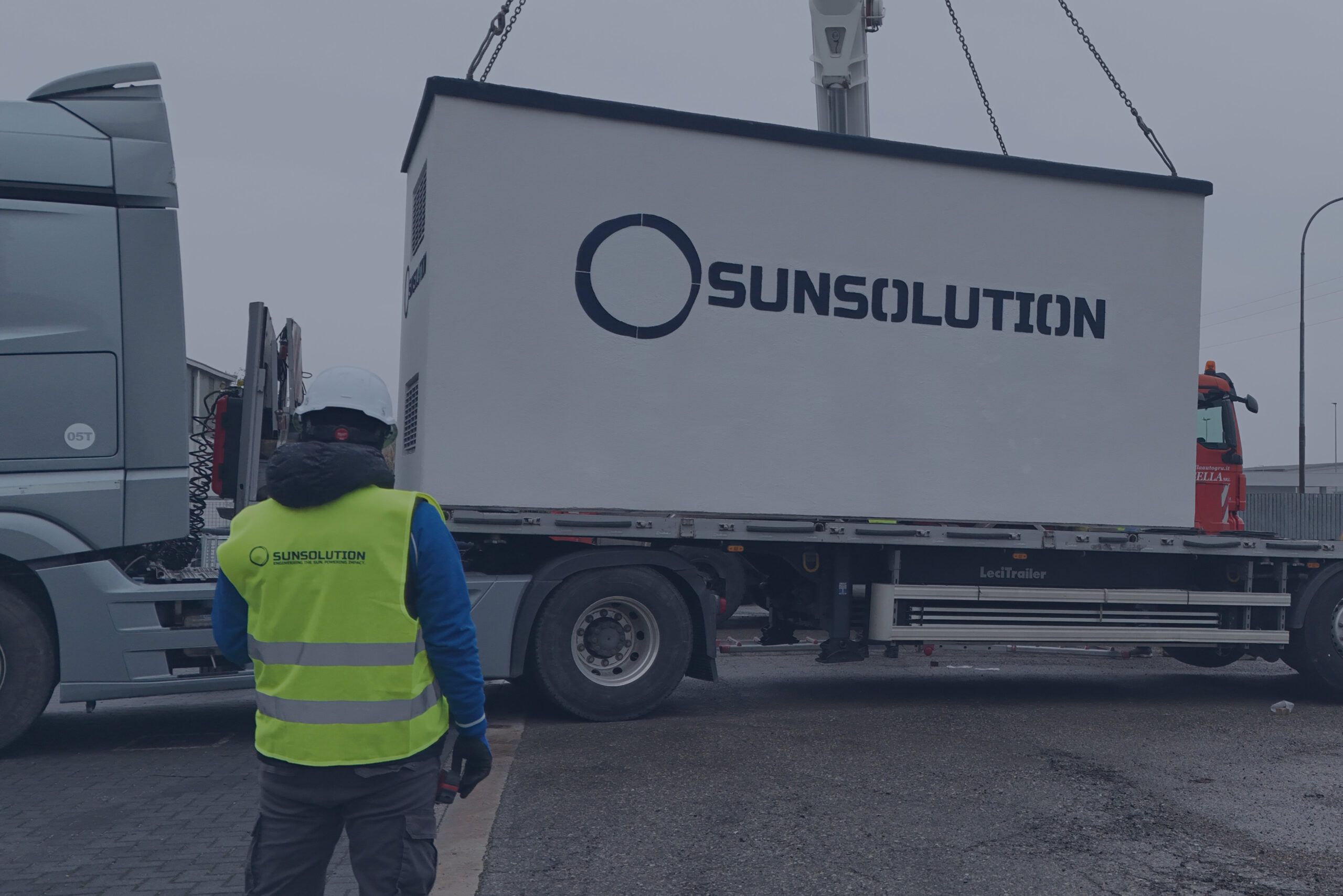 Un tecnico con regolari DPI sta posizionando un pannello fotovoltaico in mezzo ad altri pannelli.