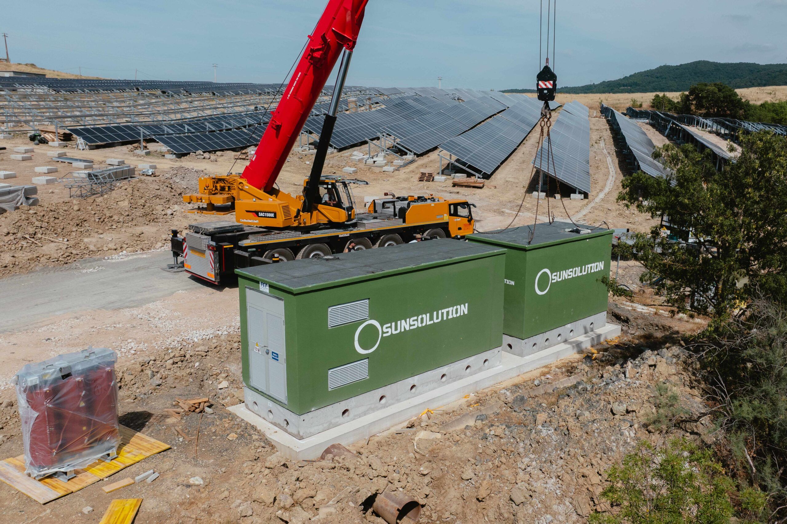 Un tecnico con regolari DPI sta posizionando un pannello fotovoltaico in mezzo ad altri pannelli.