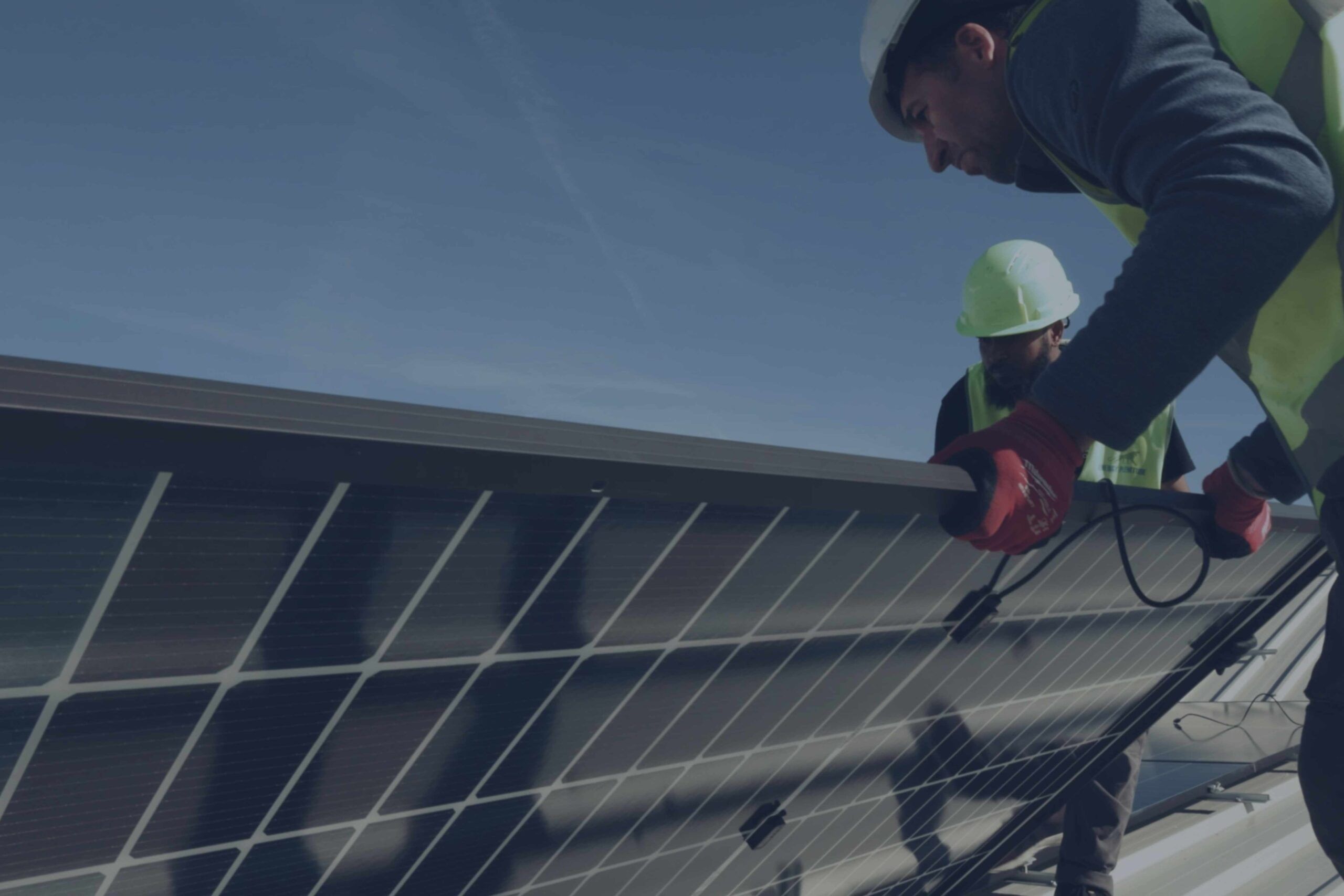 Un tecnico con regolari DPI sta posizionando un pannello fotovoltaico in mezzo ad altri pannelli.