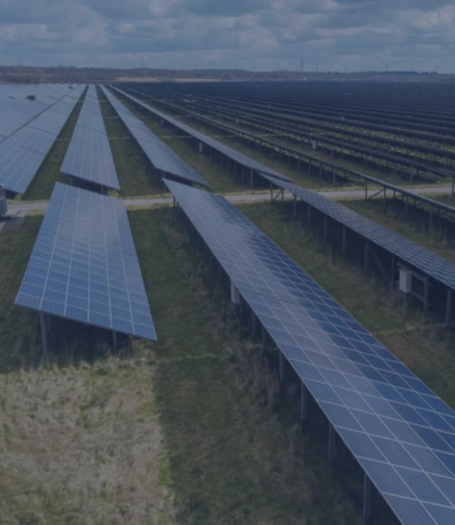 Serie di stringhe fotovoltaiche di un impianto fotovoltaico a terra installato su un terreno inutilizzato in aperta campagna.